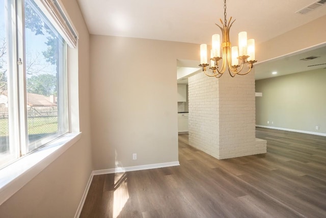 unfurnished dining area with wood finished floors, an inviting chandelier, baseboards, and plenty of natural light