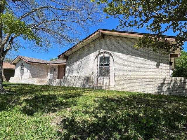 604 E Kerr St, Burnet, TX 78611 - view of home's exterior featuring brick siding and a lawn