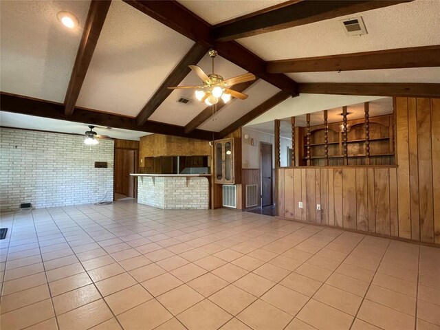 604 E Kerr St, Burnet, TX 78611 - unfurnished living room featuring ceiling fan, wood walls, light tile patterned floors, and brick wall