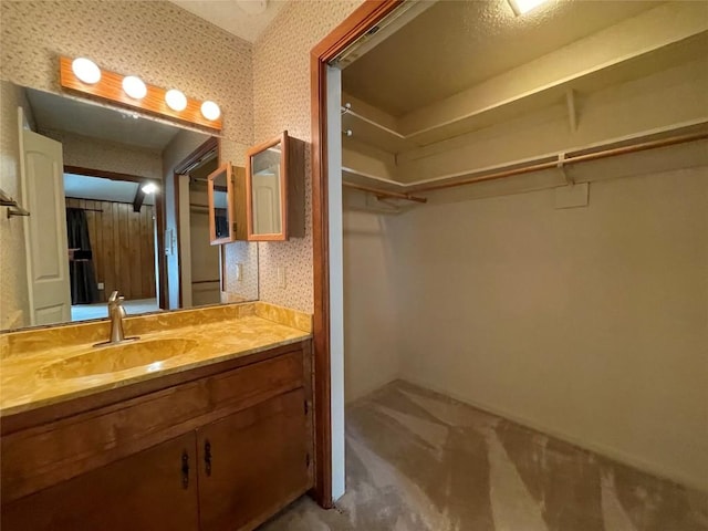 604 E Kerr St, Burnet, TX 78611 - bathroom featuring vanity, wallpapered walls, and a spacious closet