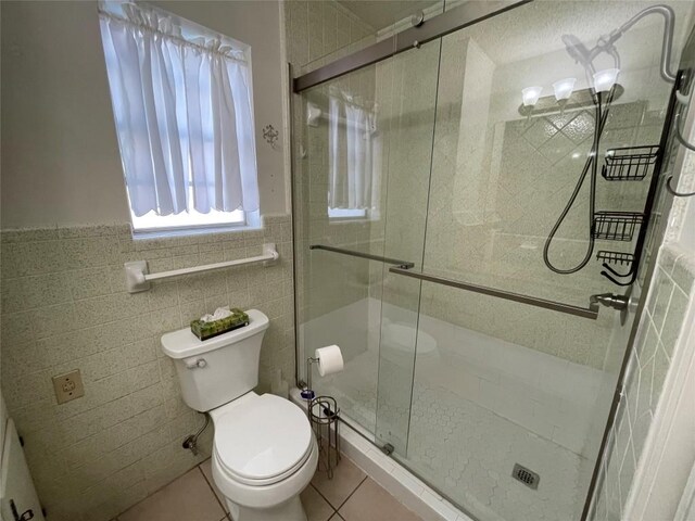 604 E Kerr St, Burnet, TX 78611 - bathroom with tile patterned floors, a shower stall, a wainscoted wall, and tile walls