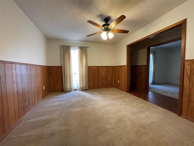 604 E Kerr St, Burnet, TX 78611 - carpeted spare room with a wainscoted wall, ceiling fan, a textured ceiling, and wood walls