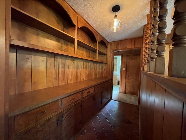 604 E Kerr St, Burnet, TX 78611 - hall featuring a textured ceiling, wooden walls, and dark tile patterned flooring
