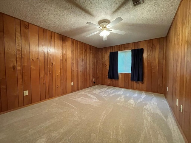 604 E Kerr St, Burnet, TX 78611 - empty room with carpet floors, ceiling fan, a textured ceiling, and wood walls