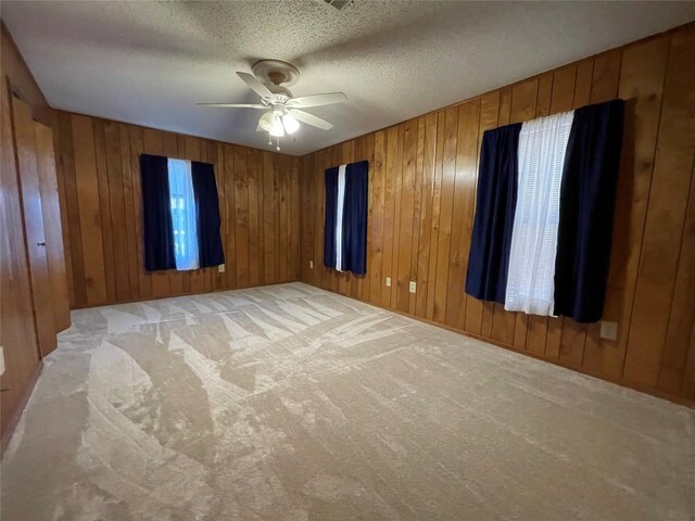 604 E Kerr St, Burnet, TX 78611 - spare room featuring a ceiling fan, light colored carpet, wooden walls, and a textured ceiling