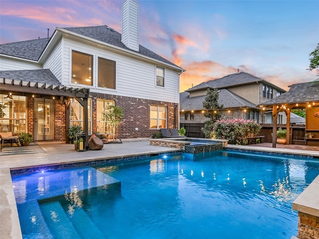 pool at dusk with a pergola, a patio area, a pool with connected hot tub, and fence