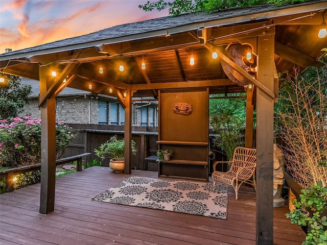 deck at dusk with fence and a gazebo