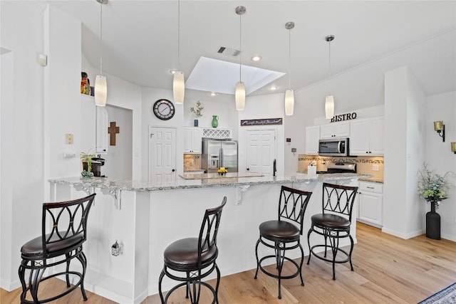 4010 Halfway Cv, Round Rock, TX 78681 - kitchen featuring a kitchen bar, white cabinets, visible vents, stainless steel appliances, and light wood finished floors