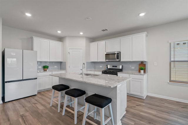 506 Windy Reed Rd, Hutto, TX 78634 - kitchen with stainless steel appliances, decorative backsplash, light wood finished floors, white cabinets, and recessed lighting