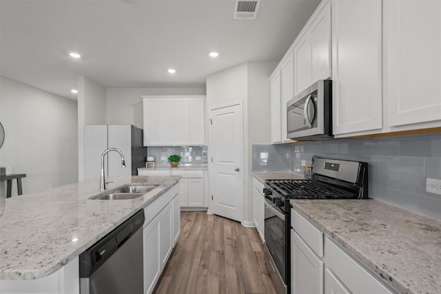 506 Windy Reed Rd, Hutto, TX 78634 - kitchen with appliances with stainless steel finishes, light wood-style floors, recessed lighting, tasteful backsplash, and white cabinetry