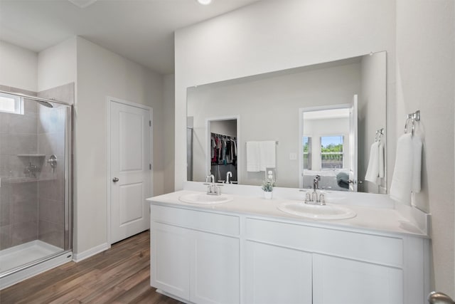 506 Windy Reed Rd, Hutto, TX 78634 - bathroom featuring a shower stall, double vanity, wood finished floors, and a walk in closet