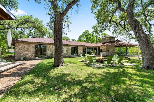 5322 Western Hills Dr, Austin, TX 78731 - rear view of house featuring a fire pit, stone siding, a patio, and a lawn