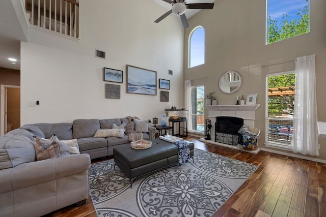 20300 Wayzata Ct, Pflugerville, TX 78660 - living area featuring a towering ceiling, a ceiling fan, hardwood / wood-style flooring, and a fireplace with raised hearth