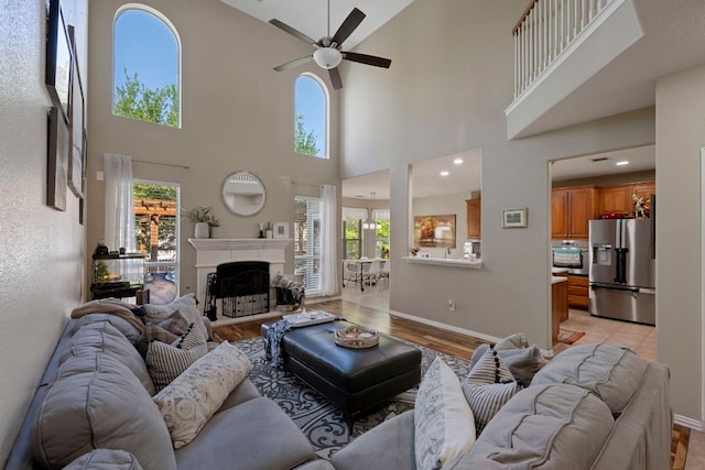 20300 Wayzata Ct, Pflugerville, TX 78660 - living area featuring healthy amount of natural light, a ceiling fan, a towering ceiling, a fireplace, and light wood-style flooring