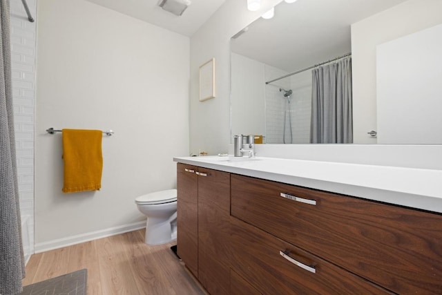 bathroom with baseboards, curtained shower, toilet, vanity, and wood finished floors