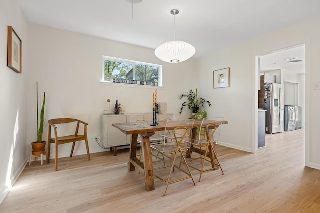 dining space with washer / clothes dryer, light wood-style flooring, and baseboards