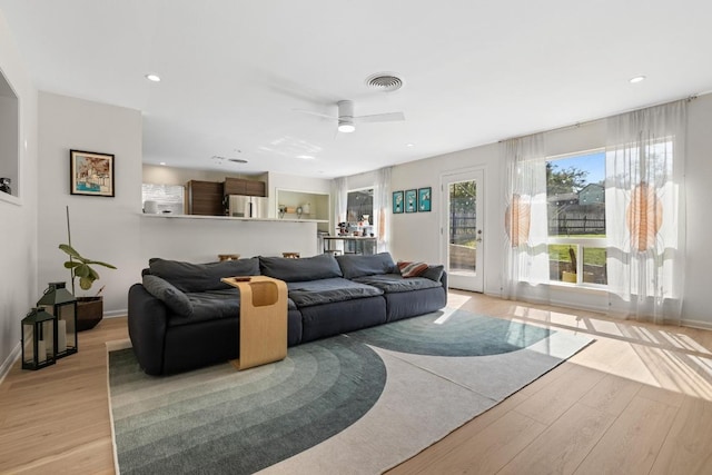 living room featuring light wood-style floors, ceiling fan, baseboards, and visible vents