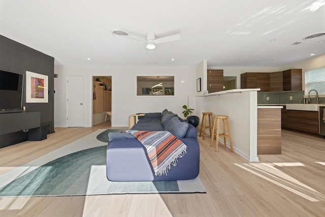 living room featuring visible vents, ceiling fan, light wood-style floors, and baseboards