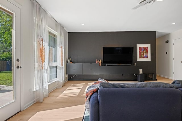living area with visible vents, baseboards, an accent wall, light wood-type flooring, and recessed lighting