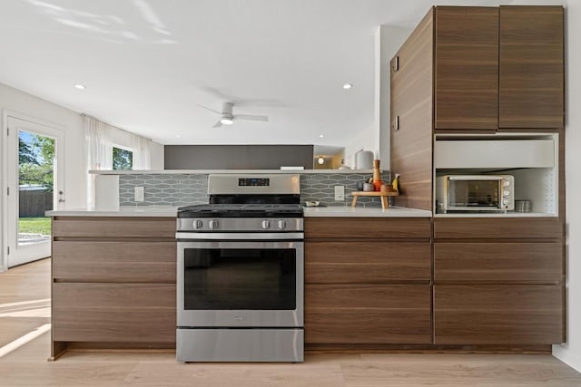 kitchen with decorative backsplash, ceiling fan, gas stove, and light countertops