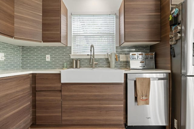 kitchen featuring light countertops, a sink, backsplash, and appliances with stainless steel finishes