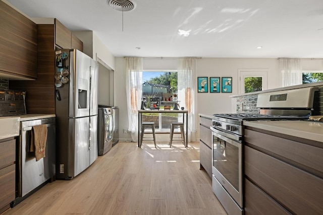 kitchen with washer / clothes dryer, visible vents, light countertops, appliances with stainless steel finishes, and light wood-style flooring