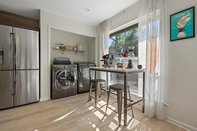 laundry room featuring baseboards, light wood-type flooring, washer and dryer, and laundry area