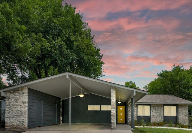 mid-century inspired home with stone siding, an attached carport, and concrete driveway