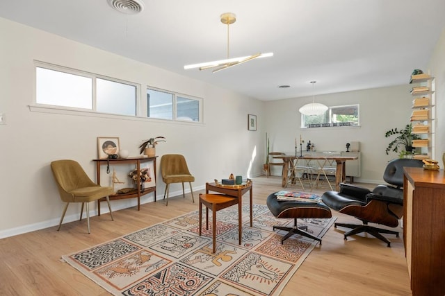 sitting room with light wood-type flooring, visible vents, and baseboards