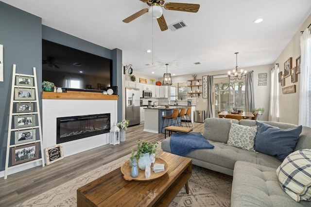 116 Buttercup Trl, Georgetown, TX 78633 - living area featuring ceiling fan, wood finished floors, a glass covered fireplace, a chandelier, and recessed lighting