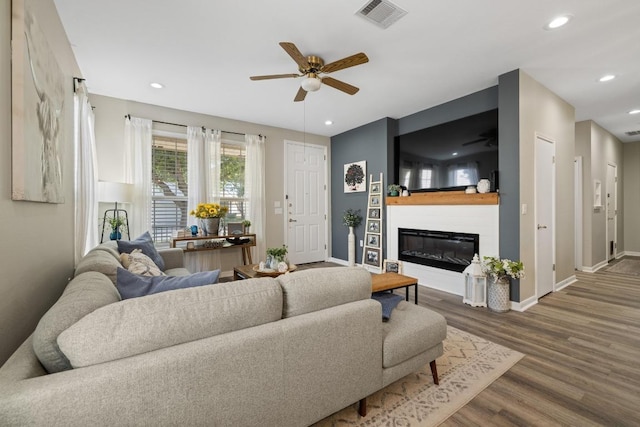 116 Buttercup Trl, Georgetown, TX 78633 - living room featuring a ceiling fan, wood finished floors, a glass covered fireplace, and recessed lighting