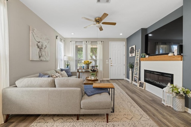 116 Buttercup Trl, Georgetown, TX 78633 - living room featuring wood finished floors, a ceiling fan, a glass covered fireplace, and recessed lighting