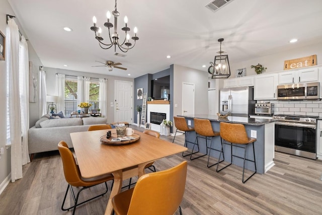 116 Buttercup Trl, Georgetown, TX 78633 - dining space with a chandelier, light wood-style flooring, recessed lighting, a glass covered fireplace, and ceiling fan