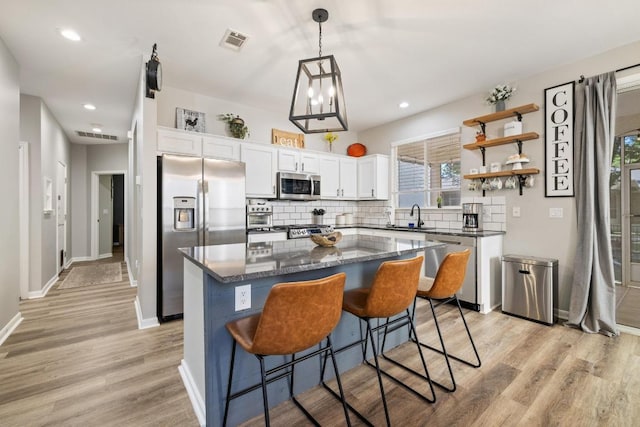 116 Buttercup Trl, Georgetown, TX 78633 - kitchen featuring appliances with stainless steel finishes, a center island, white cabinetry, decorative backsplash, and light wood finished floors