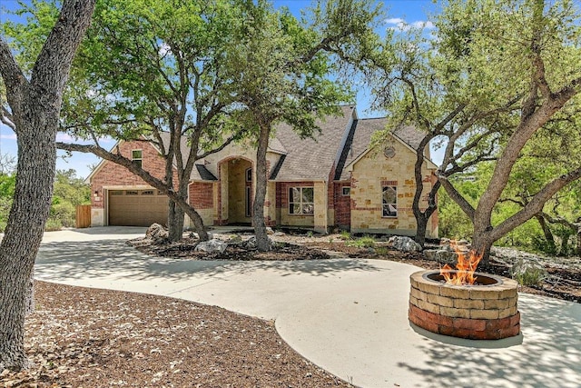 view of front of house with brick siding, an attached garage, stone siding, and concrete driveway