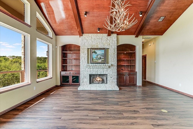 unfurnished living room featuring a chandelier, a stone fireplace, built in features, and wood finished floors