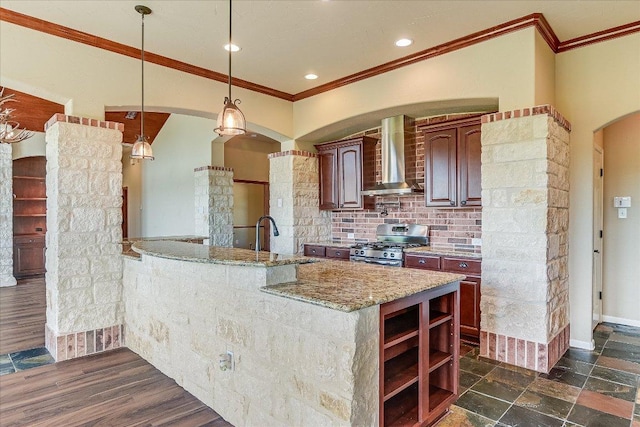 kitchen with a sink, crown molding, stainless steel range with gas stovetop, and wall chimney range hood