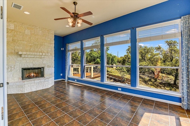 unfurnished living room featuring a ceiling fan, visible vents, a stone fireplace, recessed lighting, and baseboards