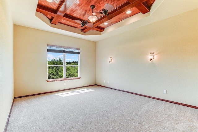 empty room with baseboards, carpet floors, beamed ceiling, ceiling fan, and wooden ceiling