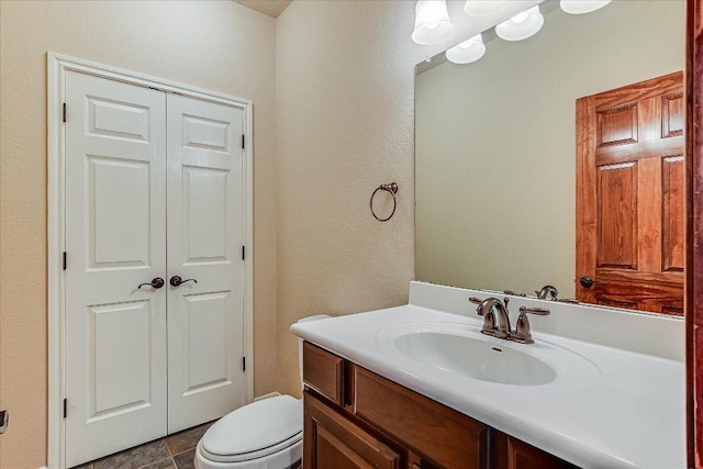 half bath featuring toilet, vanity, and a textured wall