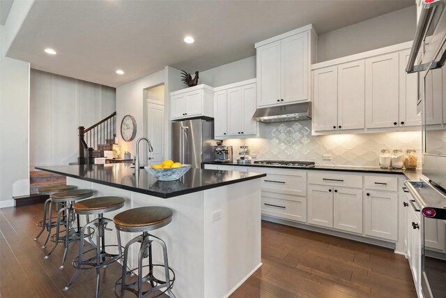 234 Sumalt Gap Way, Lakeway, TX 78738 - kitchen featuring appliances with stainless steel finishes, dark wood-type flooring, dark countertops, under cabinet range hood, and recessed lighting