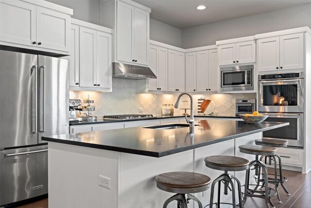 234 Sumalt Gap Way, Lakeway, TX 78738 - kitchen with stainless steel appliances, under cabinet range hood, dark countertops, dark wood-style flooring, and recessed lighting