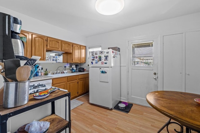 5708 Ave F, Austin, TX 78752 - kitchen with freestanding refrigerator, light wood-style flooring, light countertops, and brown cabinetry