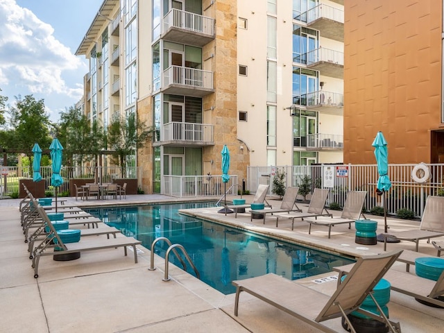 community pool with a patio area and fence