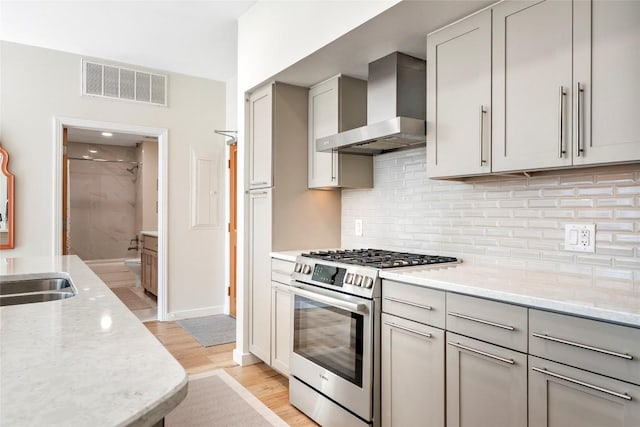 1600 Barton Springs Rd Unit 5503, Austin, TX 78704 - kitchen featuring stainless steel range with gas stovetop, wall chimney exhaust hood, gray cabinets, and light stone counters
