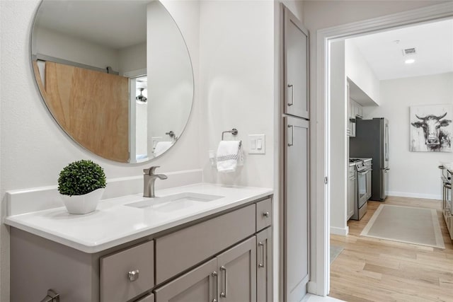 bathroom featuring wood finished floors, vanity, baseboards, and visible vents