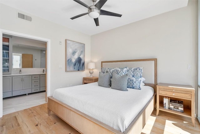 bedroom featuring visible vents, ceiling fan, ensuite bathroom, and light wood-style flooring