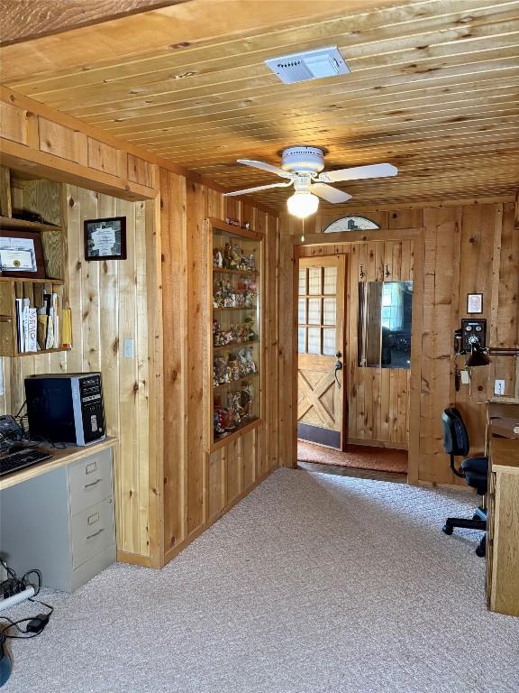 unfurnished office with visible vents, a ceiling fan, carpet, wood ceiling, and wood walls