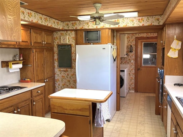 kitchen featuring brown cabinets, wallpapered walls, and freestanding refrigerator