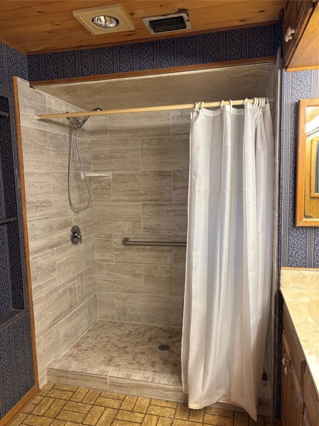 full bathroom featuring brick floor, wallpapered walls, vanity, and tiled shower